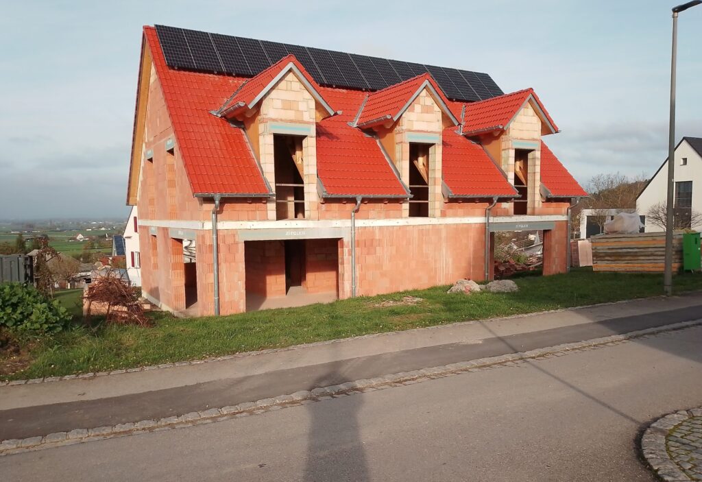 Rohbau eines modernen Mehrfamilienhauses mit roten Ziegeldächern – BauPlusIngenieure Neuötting